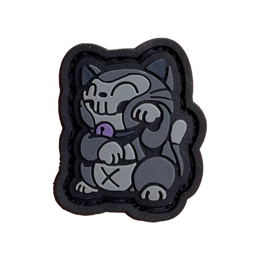 A black and gray cat in the Neko (lucky cat) pose, with a purple bell and an 'X' on his belly. 