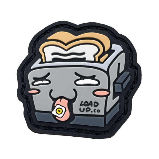 Adorable toaster patch featuring a toast popping out, adorned with a playful face and a tongue extended with a square piece of paper on top.